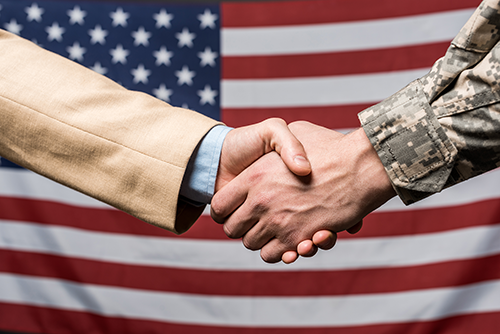 Military man and business man shaking hands with an American flag in the background