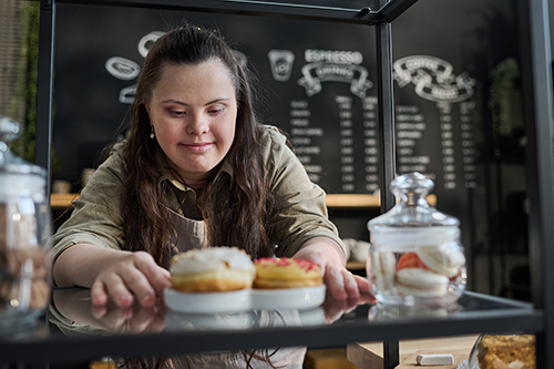 Woman with down syndrome placing donuts on tray